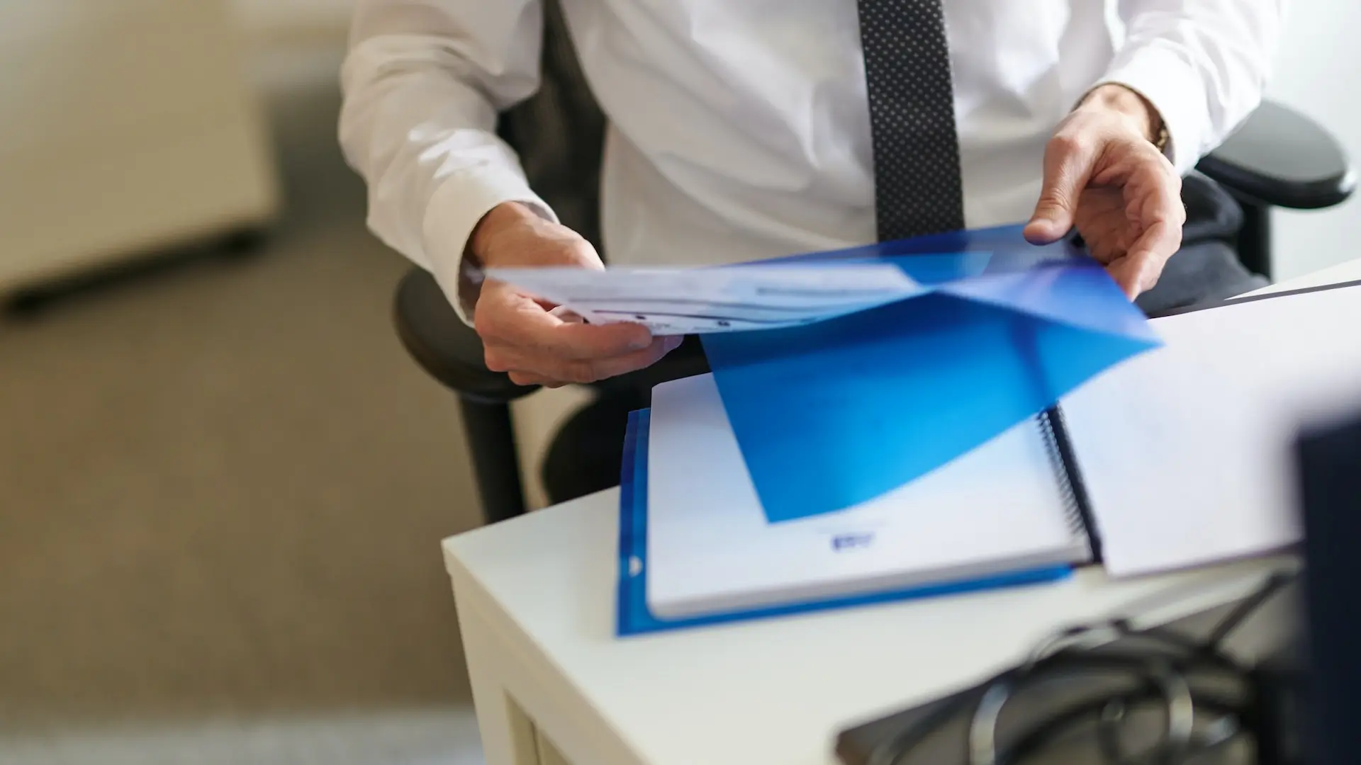 a man in a white shirt and tie holding a folder